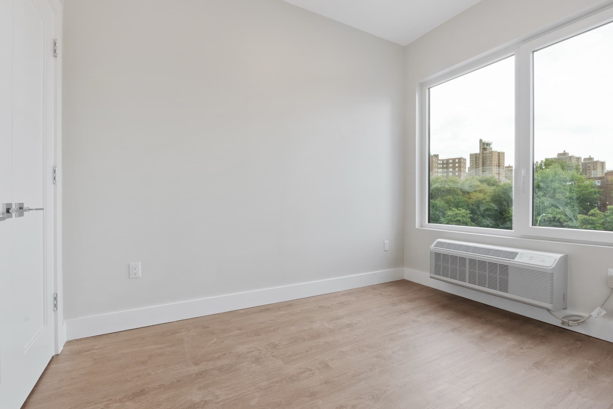 A residence bedroom at The Astelle with a window looking out over green space and the neighborhood below.