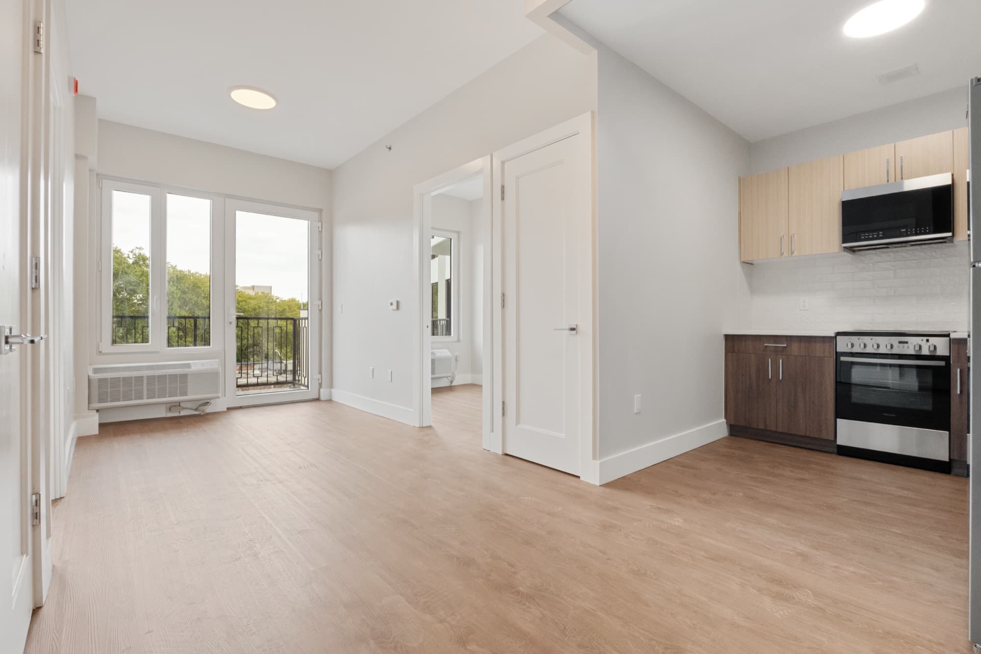 A two-bedroom residence at The Astelle, an open living room and kitchen with wide windows and pale oak floors