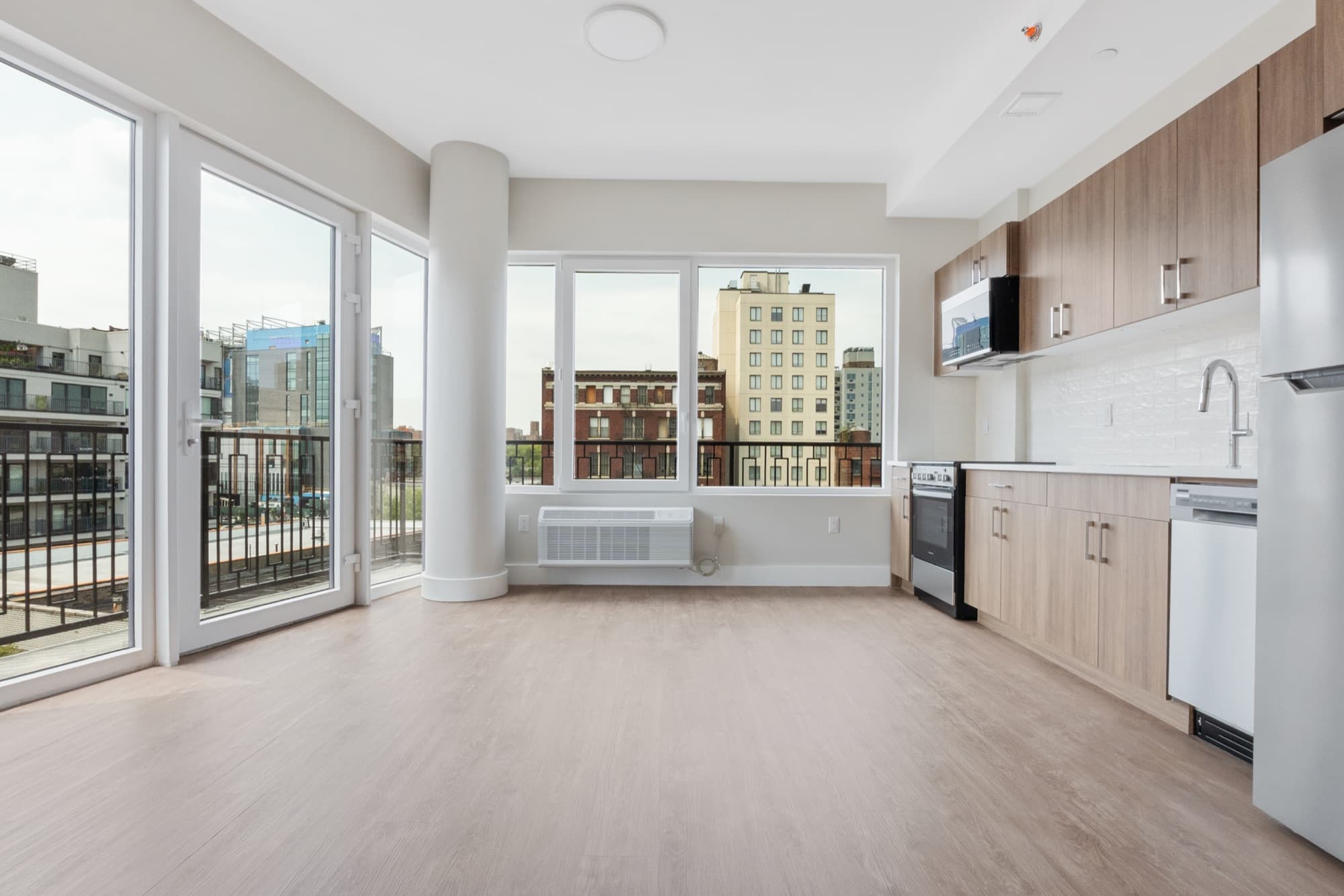 A residence at The Astelle with the kitchen open to the living room and a balcony beyond.