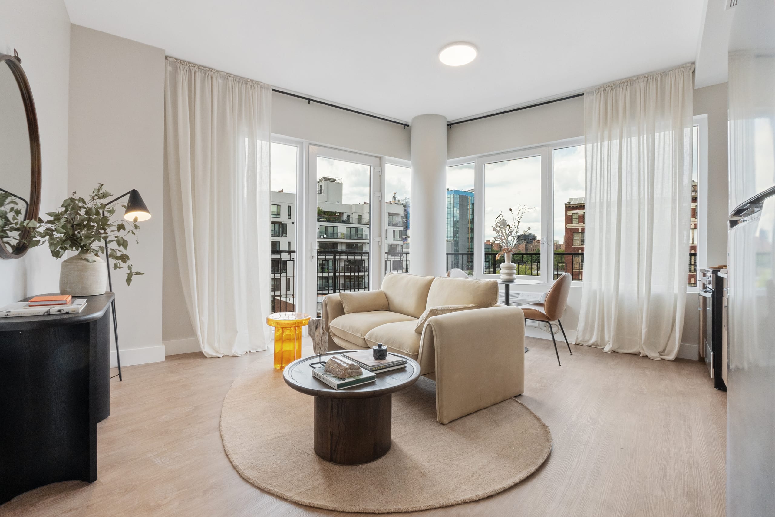 A residence at The Astelle bathed in afternoon light, with a balcony beyond floor-to-ceiling glass